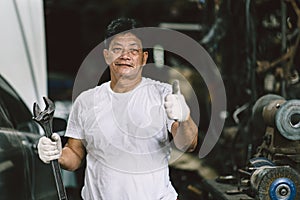 Portrait happy Asian adult male worker dirty with oil grease standing thumbs up smiling