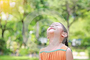 Portrait of happy Asian child close their eyes in garden with Breathe fresh air from nature. Close up kid girl relax in green park