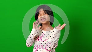 Portrait of happy Asian child girl motion to a camera on green screen background, a child looking at camera. Preschool kid