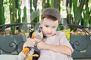 Portrait of happy Asian European boy with a lovely dog doll