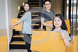 Portrait of happy Asian family moving to new house with cardboard boxes.