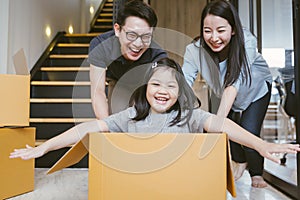 Portrait of happy Asian family moving to new house with cardboard boxes.