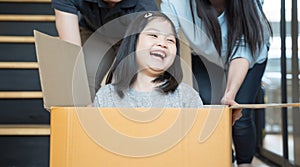 Portrait of happy Asian family moving to new house with cardboard boxes and playing cardboard box.