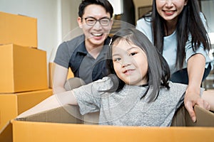 Portrait of happy Asian family moving to new house with cardboard boxes and playing cardboard box.