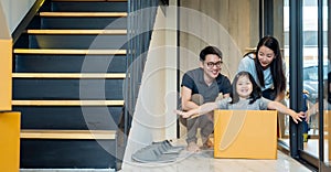 Portrait of happy Asian family moving to new house with cardboard boxes and playing cardboard box.