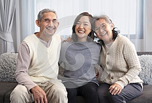 portrait happy asian family,older adult father and mother with young adult daughter sitting on couch