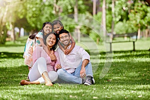 Portrait of happy asian family in the park. Adorable little girls bonding and hugging their parents outside in a park