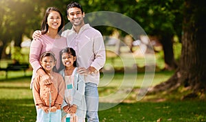 Portrait of happy asian family relaxing and sharing quality time on a sunny day in nature in a park or garden with