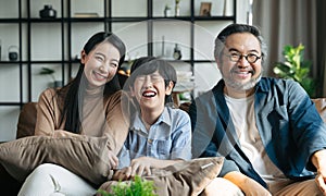Portrait of happy Asian family spending time together on sofa in living room. family and home concept.