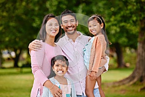 Portrait of happy asian family standing close together in a park. Adorable little girls enjoying free time with their