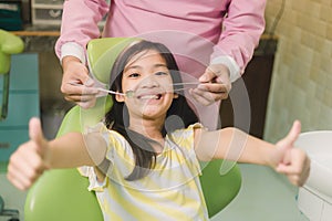 Portrait of happy asian girl shows thumb up gesture at dental clinic