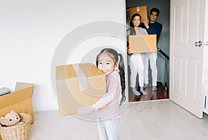 Portrait of a happy asian little daughter carrying boxes into the a new home on moving day. Happy Family move on a new home