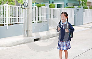 Portrait of happy asian little kid girl in school uniform walking on street leave home to go to school at morning