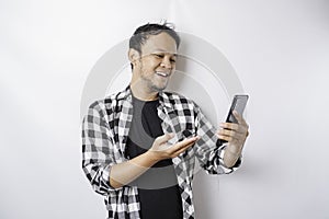 A portrait of a happy Asian man is smiling while holding on his phone, isolated by white background