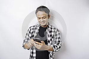 A portrait of a happy Asian man is smiling while holding on his phone, isolated by white background