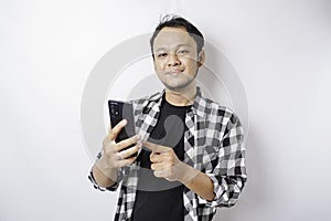 A portrait of a happy Asian man is smiling while holding on his phone, isolated by white background