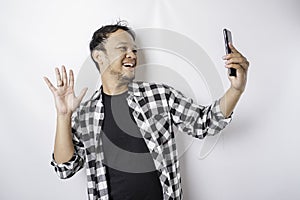 A portrait of a happy Asian man is smiling while holding on his phone, isolated by white background