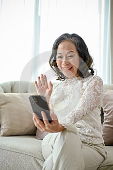 Portrait, Happy Asian middle-aged woman uses her smartphone to video call