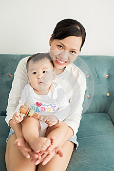 Portrait of happy asian mother and baby having fun together at h