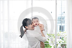 Portrait of happy asian mother and baby having fun together at h