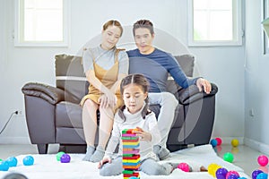 Portrait of happy asian parent looking at their daughter smiling playing with toy build wooden blocks board game in moments good