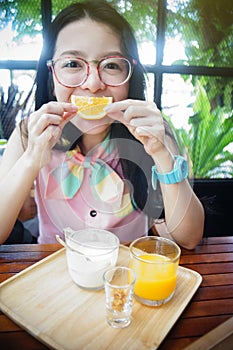 Portrait of happy asian woman in a cafe with orange fruits against of a mouth like a smile,say cheese concept,happy with food