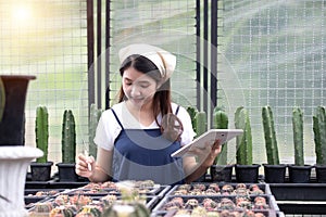 Portrait of happy Asian woman holding tablet fos checking the number of cacti to sell to customers at his cactus shop