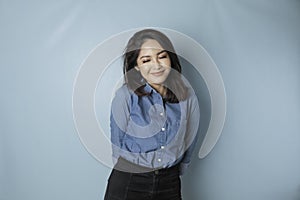 A portrait of a happy Asian woman is smiling and wearing a blue shirt isolated by a blue background