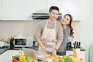 Portrait of happy asian young couple cooking together in the kit