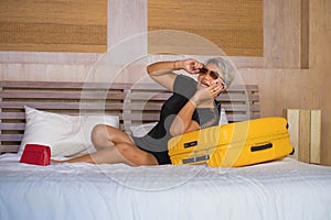 Portrait of happy and attractive mature Asian tourist woman with grey hair arriving in hotel room excited on bed having fun