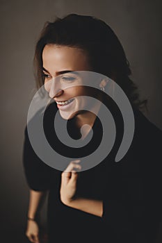 Portrait of happy attractive woman wearing black shirt. Brunette curly hair woman. Woman look at side.