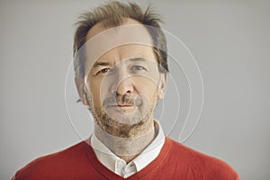 Portrait of happy balding senior man looking at camera on grey studio background