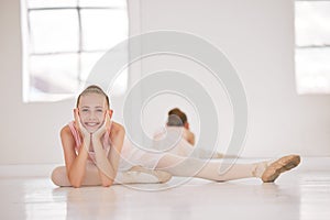 Portrait of happy ballet dancer on a break from training in a dance studio, smiling and stretching. Excited, flexible