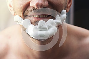 Portrait of happy bearded handsome man with shaving foam on his face