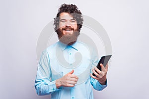 Portrait of happy bearded and handsome man using tablet over white wall