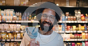 Portrait of happy bearded man in 30s smiling while looking to camera. Close up of mature guy in glasses putting jacket