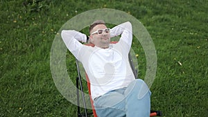 Portrait of happy bearded man looking camera with smile relaxes alone at city park. Smiling young man tourist using