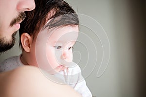 Portrait of happy beautiful baby girl sitting oh fathers hands