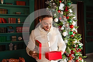 Portrait of happy beautiful emotional man opening Christmas gift box