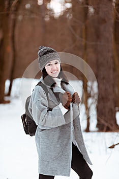 Portrait of a happy beautiful girl with brown hair in the winter forest dressed in a hipster style, lifestyle
