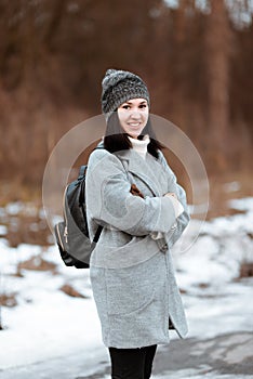 Portrait of a happy beautiful girl with brown hair in the winter forest dressed in a hipster style, lifestyle