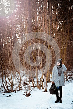 Portrait of a happy beautiful girl with brown hair in the winter forest dressed in a hipster style, lifestyle