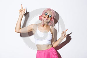 Portrait of happy beautiful girl having fun, dancing and smiling, celebrating holiday on party, wearing pink wig with