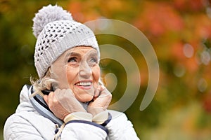 Portrait of happy beautiful senior woman posing in autumn park