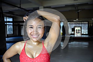 portrait of happy beautiful and sweaty young Asian woman in sport training cloths smiling relaxed at gym