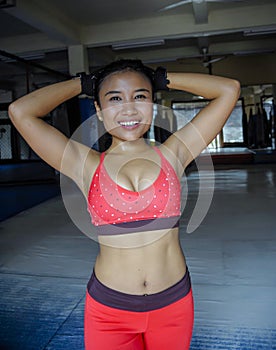 Portrait of happy beautiful and sweaty young Asian woman in sport training cloths smiling relaxed at gym