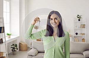 Portrait of happy beautiful young female homeowner showing keys to her new home.