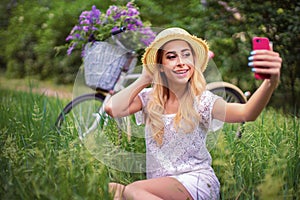 Beautiful young girl with vintage bicycle and flowers on city background in the sunlight outdoor.