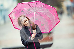 Portrait of happy beautiful young pre-teen girl with pink umbrella under rain