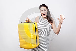 Portrait of happy beautiful young traveller in striped dress sta